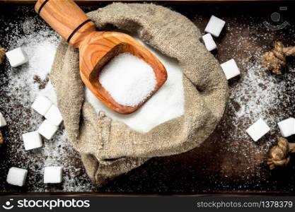 Sugar in an old sack with a scoop. On a rustic background.. Sugar in an old sack with a scoop.