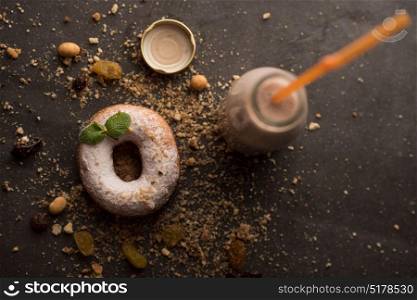 Sugar powder Donut with mint leaf and milk bottle on dark stone background