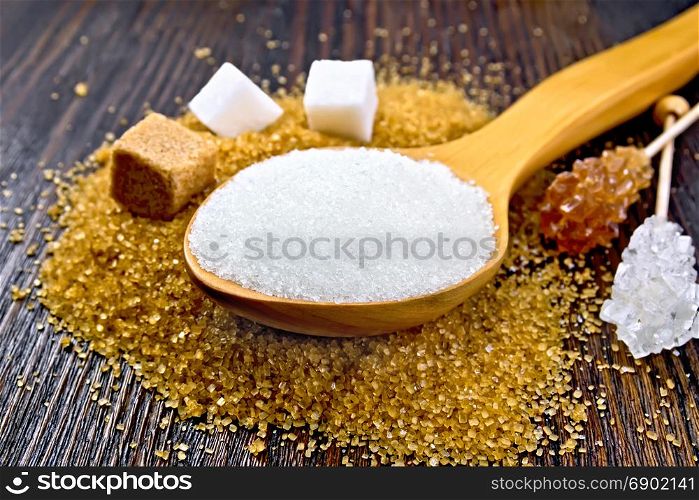 Sugar white and brown in cubes, crystal on a stick and granulated in a spoon on a wooden plank background