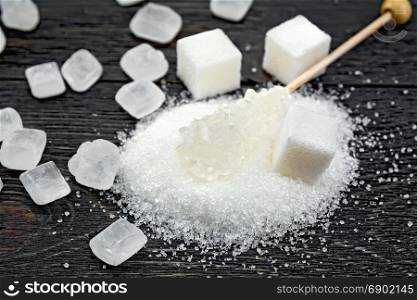 Sugar white granular, crystalline and cubes on the background of a black wooden board