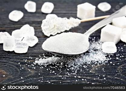 Sugar white granulated in a metal spoon, crystal and cubes on a wooden plank background
