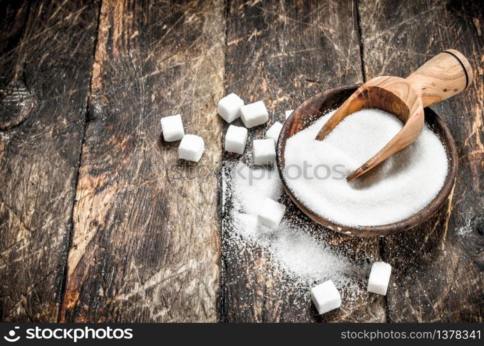 Sugar with a scoop in a bowl. On a wooden background.. Sugar with a scoop in a bowl.