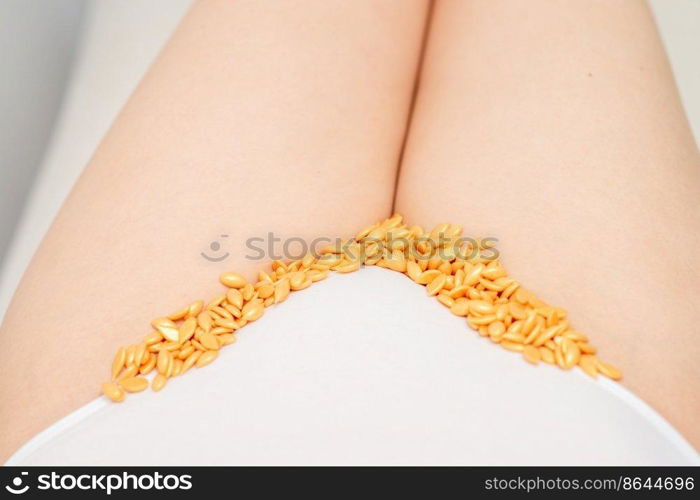 Sugaring concept. Wax granules lying in a row on female bikini area close up. Sugaring concept. Wax granules lying in a row on female bikini area close up.