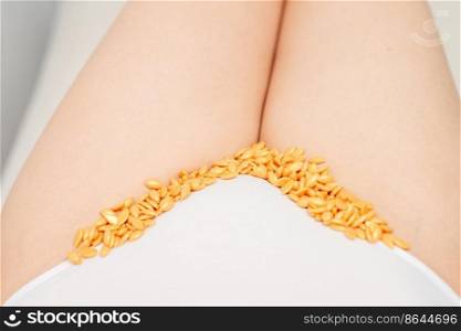 Sugaring concept. Wax granules lying in a row on female bikini area close up. Sugaring concept. Wax granules lying in a row on female bikini area close up.