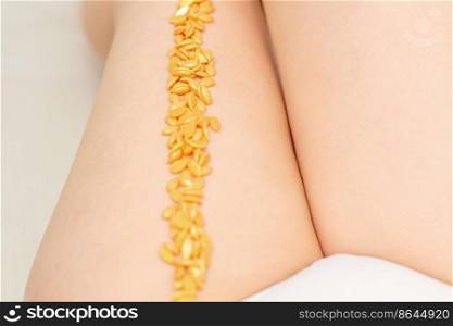 Sugaring concept. Wax granules lying in a row on female legs close up. Sugaring concept. Wax granules lying in a row on female legs close up.
