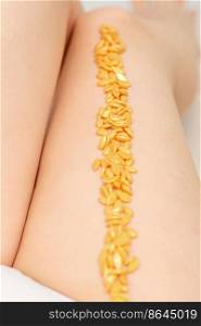 Sugaring concept. Wax granules lying in a row on female legs close up. Sugaring concept. Wax granules lying in a row on female legs close up.