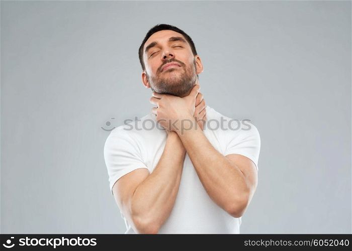 suicide, despair, death and people concept - young man choking himself by hands over gray background