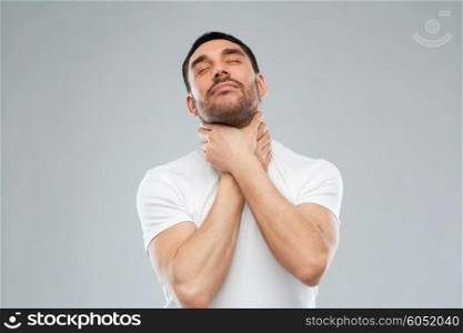 suicide, despair, death and people concept - young man choking himself by hands over gray background