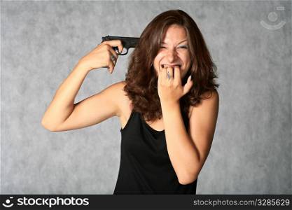 suicide - portrait of sexy brunette with pistol on the grey background