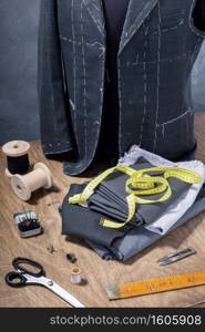 suit jacket on male tailor mannequin and sewing tools, creative concept of clothes atelier