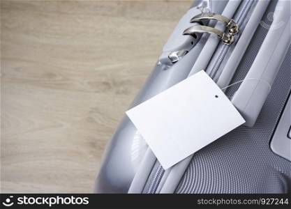 Suitcase with blank tag label on wooden floor