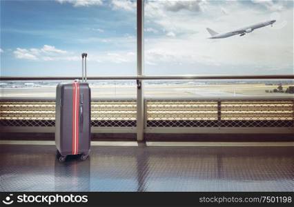Suitcases in airport departure lounge, airplane in background, summer vacation concept, traveler suitcases in airport terminal waiting area.