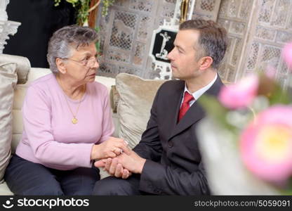 Suited man holding hands of elderly lady