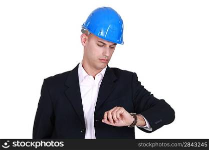 Suited man in a hardhat looking at his watch