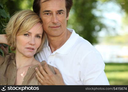 Sultry couple stood by tree in park