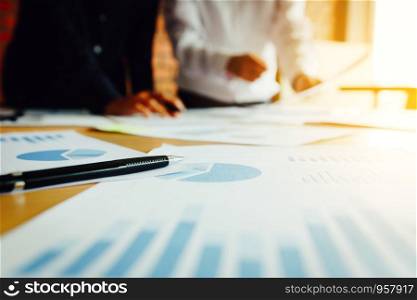 Summary report graph and two businessmen in a meeting and standing at boardroom table background.