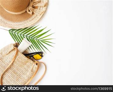 Summer accessories concept from sunglasses, straw hat and tropical palm leaf branches on white background with empty space for text.