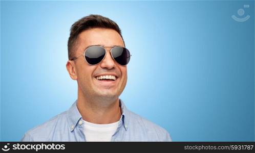 summer, accessories, style and people concept - face of smiling middle aged latin man in shirt and sunglasses over blue background