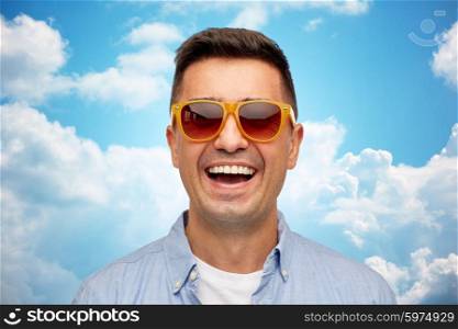 summer, accessories, style and people concept - face of smiling middle aged latin man in shirt and sunglasses over blue sky and clouds background