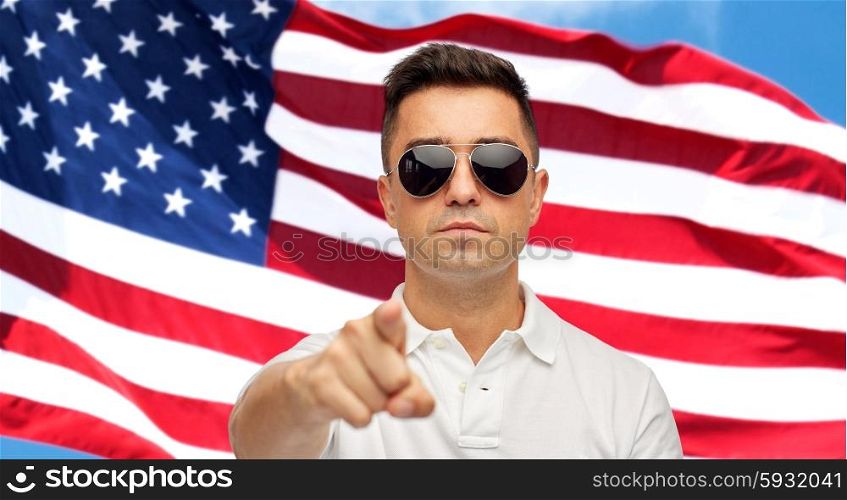 summer, accessories, style, gesture and people concept - face of middle aged latin man in white polo t-shirt and sunglasses pointing finger on you over american flag background