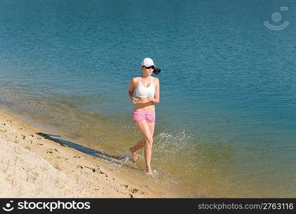 Summer active woman jogging on beach seashore in fitness outfit