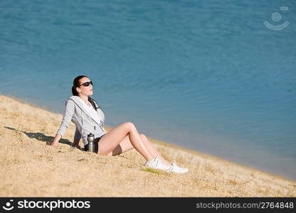 Summer active woman sit on beach sunset in fitness outfit