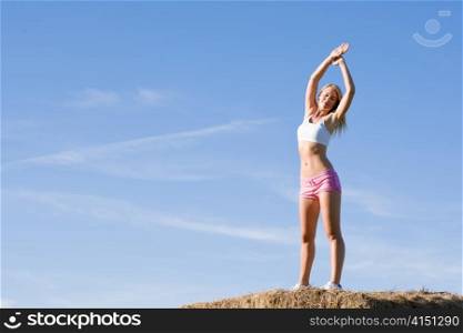 Summer active woman stretching on bales in fitness outfit