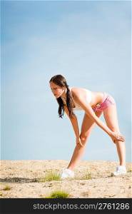 Summer active woman stretching on beach in fitness outfit
