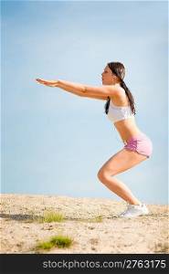 Summer active woman stretching on beach in fitness outfit