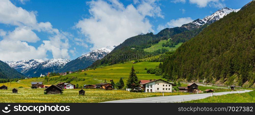 Summer Alpine mountain country view with grassy meadow and road to village  Austria 