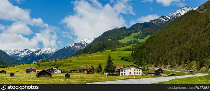 Summer Alpine mountain country view with grassy meadow and road to village  Austria 