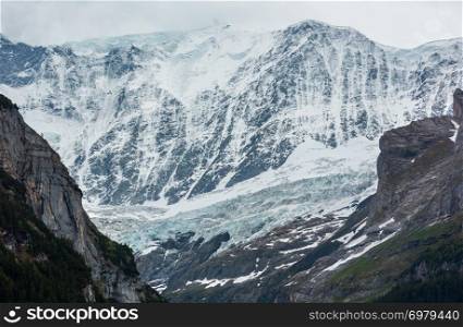 Summer Alps mountain landscape with glacier and snow covered rocky tops in far, Switzerland.