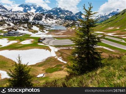 Summer Alps mountain view to small Kalbelesee lake and parking at Hochtannbergpass and snow thawing meadow (Warth, Vorarlberg, Austria).
