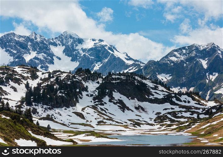 Summer Alps mountain view to small Kalbelesee lake at Hochtannbergpass and snow thawing meadow (Warth, Vorarlberg, Austria).