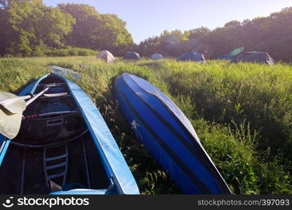 summer and active sport. tents stand in a meadow and kayak in the foreground