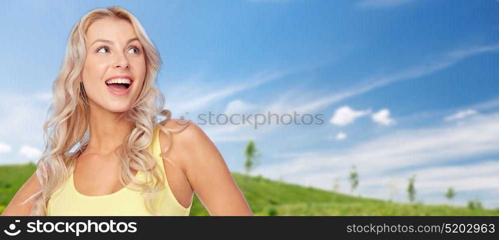 summer and people concept - happy smiling beautiful young woman with blonde hair over blue sky and green field background. smiling young woman with blonde hair in summer