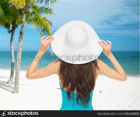 summer and vacation concept - woman sitting in swimsuit with hat