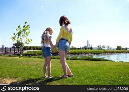 summer and vacation, girls sisters on the meadow near the river
