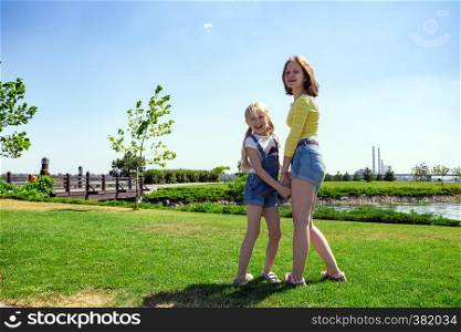 summer and vacation, Smiling happy girls sisters on the meadow near the river