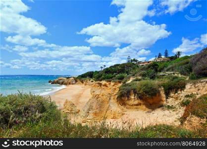 Summer Atlantic rocky coast view with house on shore and sandy beach (Albufeira outskirts, Algarve, Portugal).