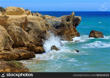 Summer Atlantic rocky coast view with splashes from waves (Albufeira outskirts, Algarve, Portugal).