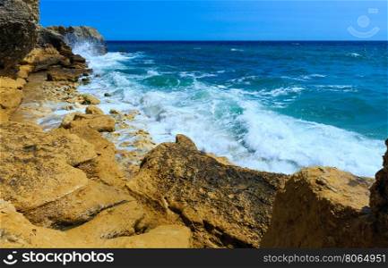 Summer Atlantic rocky coast view with with splashes from waves (Albufeira outskirts, Algarve, Portugal).