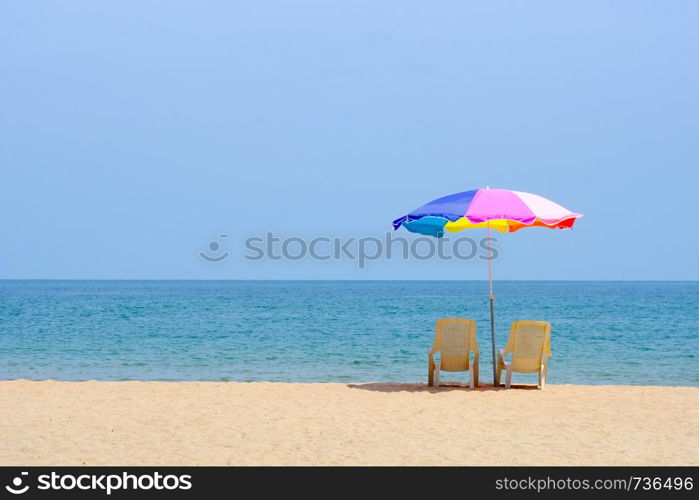 Summer background, chair and colorful umbrella on beach and sea background with copy space