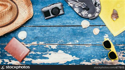 Summer background: Concept of leisure travel in the summer: Straw hat, sunglasses, shells, vintage camera, passport and flip flops. Copy space.