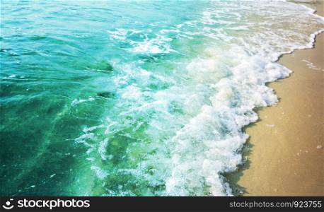 Summer background of turquoise color sea with wave on the sand beach