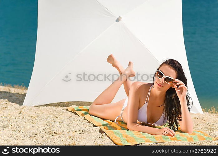 Summer beach stunning woman sunbathing in bikini parasol background