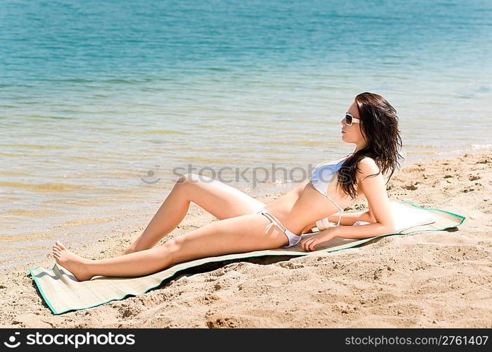 Summer beach young woman sunbathing in bikini alone