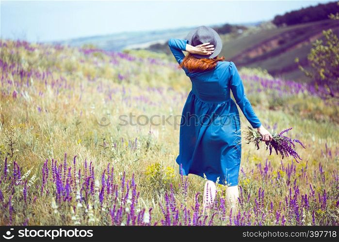 summer - beautiful girl on a meadow with a bouquet of wildflowers and traditional Ukrainian landscape