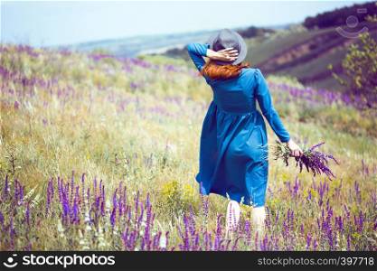 summer - beautiful girl on a meadow with a bouquet of wildflowers and traditional Ukrainian landscape