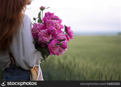summer - Beautiful girl with a bouquet peony at the field
